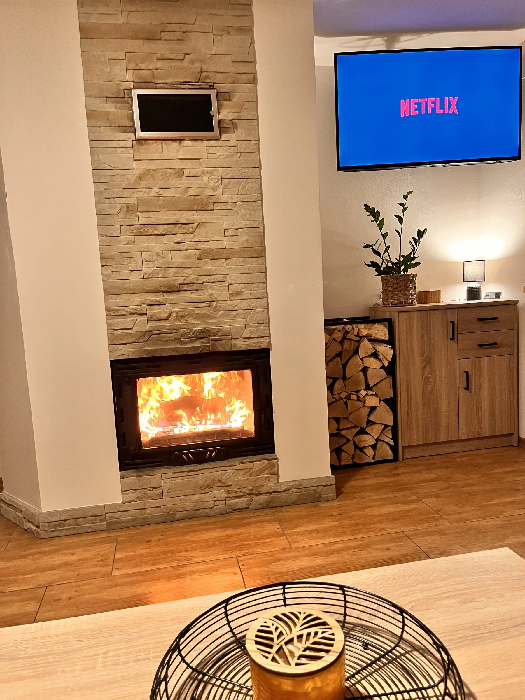 Rozpalony kominek z rozprowadzeniem ciepła i Smart TV