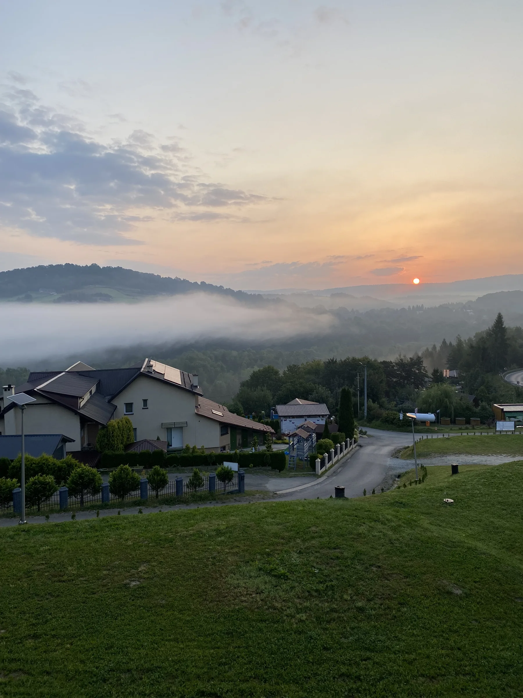 Mglisty wschód słońca nad doliną z panoramą wzgórz